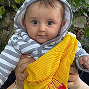 Hayden a rejoint le concours — aidez-le/la à gagner de superbes lots ! baby, child, hoodie, striped_clothing, yellow_fabric, hands, outdoor, greenery, tree_leaves, face, portrait, cute, person, smiling, holding, clothing, japanese_text, logo, closeup, infant