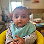 Hayden a rejoint le concours — aidez-le/la à gagner de superbes lots ! baby, child, infant, high_chair, messy_face, food, bib, blue_bib, yellow_chair, indoor, blurred_background, curious, seated, hands, long_sleeves, cute, portrait, soft_light, home, young