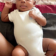 Samaj is registered to the contest to win money with this photo: baby, infant, onesie, socks, bed, blanket, patterned_sheet, person, skin, cute, child, lying_down, fist, comfortable, indoors, young, portrait, sleepwear, resting, human