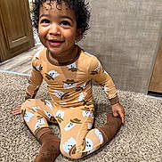 Tamãn joined the competition — help win amazing prizes! baby, brown_socks, carpet, child, cozy, curly_hair, cute, floor, ghost_pattern, happy, indoor, pajamas, person, playful, portrait, sitting, smiling, toddler, wall, wooden_door