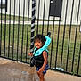 Tamãn is registered to the contest to win money with this photo: barefoot, child, clothing, curly_hair, daylight, fence, grass, happy, life_jacket, outdoor, person, play, pool_area, safety, smiling, standing, summer, toddler, water, wet_surface