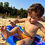 Ahadov Davud participe au concours pour gagner de l'argent avec cette photo : child, boy, beach, sand, inflatable_float, swim_trunks, summer, sunlight, water, lake, trees, outdoor, playing, barefoot, skin, daytime, vacation, young_child, relaxation, nature