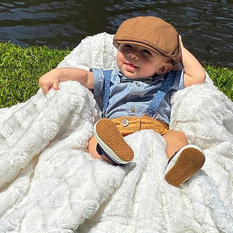 Nikolas is registered to the contest to win money with this photo: baby, baby_boy, blanket, cap, child, cute, fashion, footwear, grass, hat, nature, outdoor, portrait, relaxed, shirt, shorts, smile, sunlight, suspenders, water