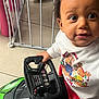 toddler, child, toy_car, steering_wheel, indoor, baby_gate, curious, festive_sweater, reindeer, red_pants, floor, hand, face, eyes, hair, clothing, play, young_child, home, fun