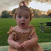 Jadynn joined the competition — help win amazing prizes! baby, child, cute, dress, expression, floral_pattern, grass, green, hair_clip, nature, orange, outdoor, park, person, picnic_table, pony_tail, sitting, sunset, toddler, trees