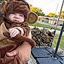 Aria joined the competition — help win amazing prizes! baby, monkey_costume, child, outdoor, firewood, dog, person, wood_deck, grass, trees, house, costume, cute, animal, pet, hand, face, smile, nature, playful