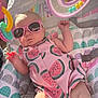 Aria is registered to the contest to win money with this photo: baby, sunglasses, infant, pink_clothing, watermelon_pattern, baby_seat, toy, colorful, sunlight, cute, child, playful, relaxing, indoors, comfort, person, portrait, summer, accessory, baby_toys