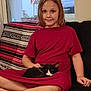 Luke is registered to the contest to win money with this photo: child, cat, indoor, couch, red_dress, black_and_white_cat, sitting, lap, blanket, window, smile, relaxed, home, furniture, curtain, pet, young, cozy, cross_legged, casual