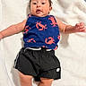 baby, infant, child, blue_tank_top, crab_pattern, black_shorts, blanket, soft_texture, lying_down, indoor, cute, expression, skin, arms, legs, face, hair, clothing, person, young