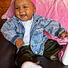 baby, child, denim_jacket, pink_headband, camo_pants, pink_sneakers, smile, happy, sitting, couch, blanket, indoor, portrait, cute, fashion, clothing, person, headwear, footwear, jacket