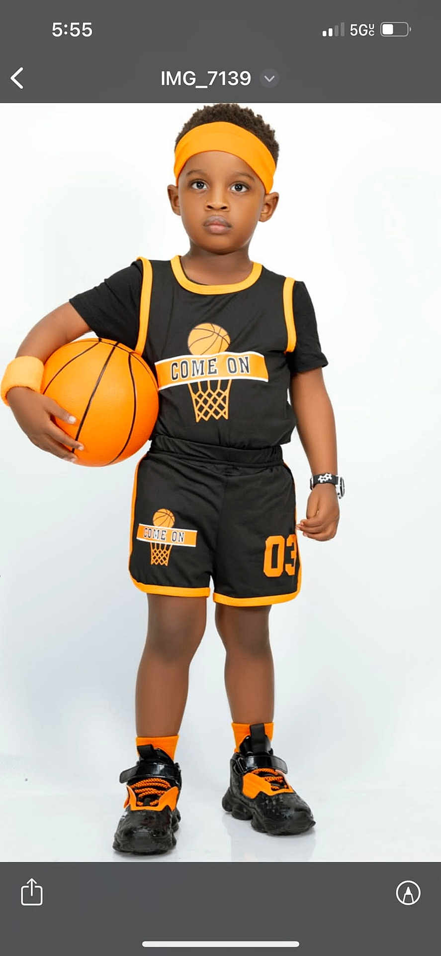 Mike is registered to the contest to win money with this photo: child, boy, basketball, basketball_uniform, headband, wristband, sneakers, socks, shorts, jersey, watch, standing, portrait, studio_shot, white_background, orange_black, sportswear, ball, shoes, serious_expression