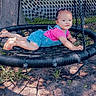 Zoey is registered to the contest to win money with this photo: blue_overalls, child, clothing, face, fence, footwear, grass, hair_clips, outdoor, person, pink_top, playground, rope_swing, shadow, shoes, summer, sunlight, swing, toddler, tree