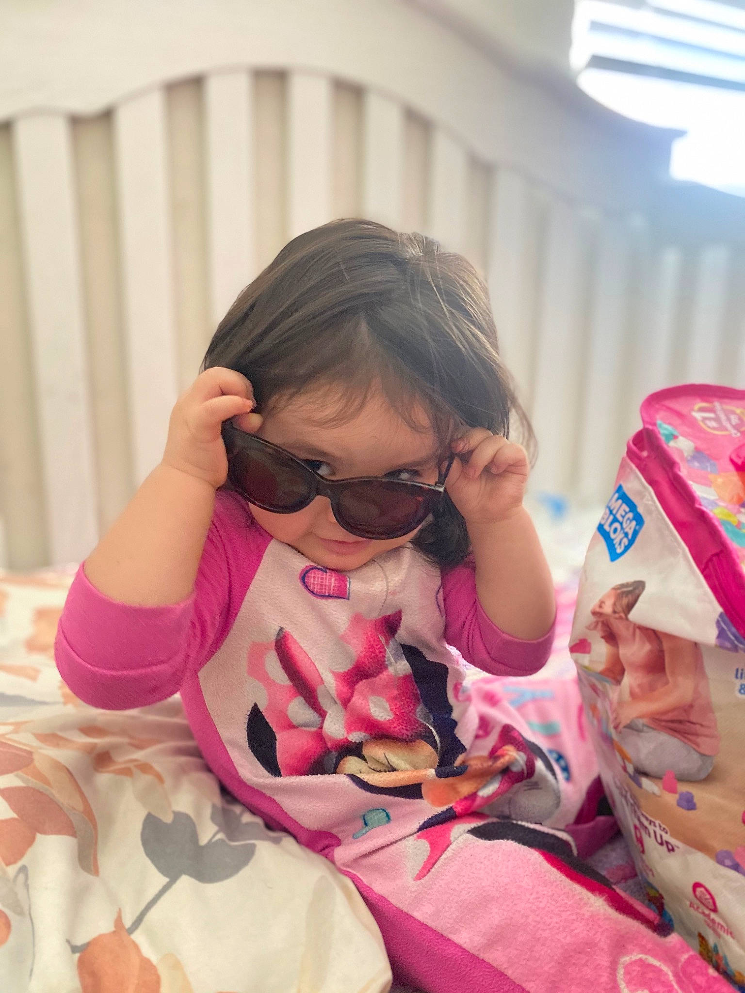 Delilah is registered to the contest to win money with this photo: baby_toddler_clothing, comfort, eyewear, fun, glasses, goggles, happy, leisure, magenta, pattern, person, personal_protective_equipment, pink, recreation, sitting, skin, sleeve, sunglasses, thigh, toddler