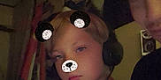 Colten joined the competition — help win amazing prizes! child, person, headphones, face_filter, bear_ears, bear_nose, indoor, dim_light, casual_clothing, red_shirt, selfie, two_people, expressionless, technology, room, wall, furniture, portrait, closeup, head
