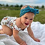 baby, headband, bow, crawling, blanket, outdoor, grass, smiling, child, happy, infant, cute, person, nature, portrait, apparel, headwear, skin, baby_clothes, daylight