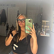 Salem is registered to the contest to win money with this photo: woman, cat, mirror, selfie, glasses, black_cat, jewelry, jewelry_stand, door, clothing, room, indoor, furniture, smartphone, long_hair, jeans, casual_wear, hand, reflection, young_adult