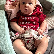 Aurora is registered to the contest to win money with this photo: baby, infant, child, blanket, clothing, red_shirt, floral_skirt, cute, sitting, indoors, soft_texture, face, expression, hands, legs, foot, portrait, childhood, cozy, adorable