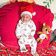Skanda is registered to the contest to win money with this photo: baby, blanket, celebration, child, christmas, cute, festive, holiday, indoors, infant, lying_down, pajamas, plush_toy, red_cushion, reindeer, santa_hat, sleepwear, smiling, soft_toy, toy_car
