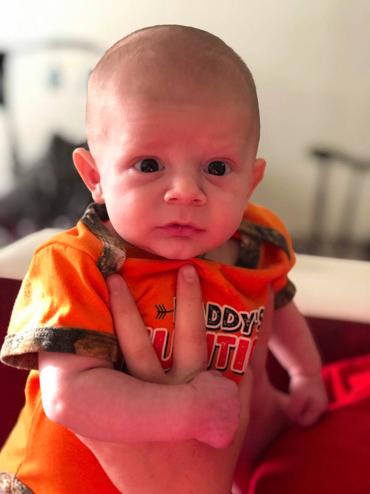 Emmett is registered to the contest to win money with this photo: baby, cheek, child, chin, ear, eye, face, finger, forehead, head, lip, mouth, neck, nose, orange, person, personal_protective_equipment, skin, smile, toddler