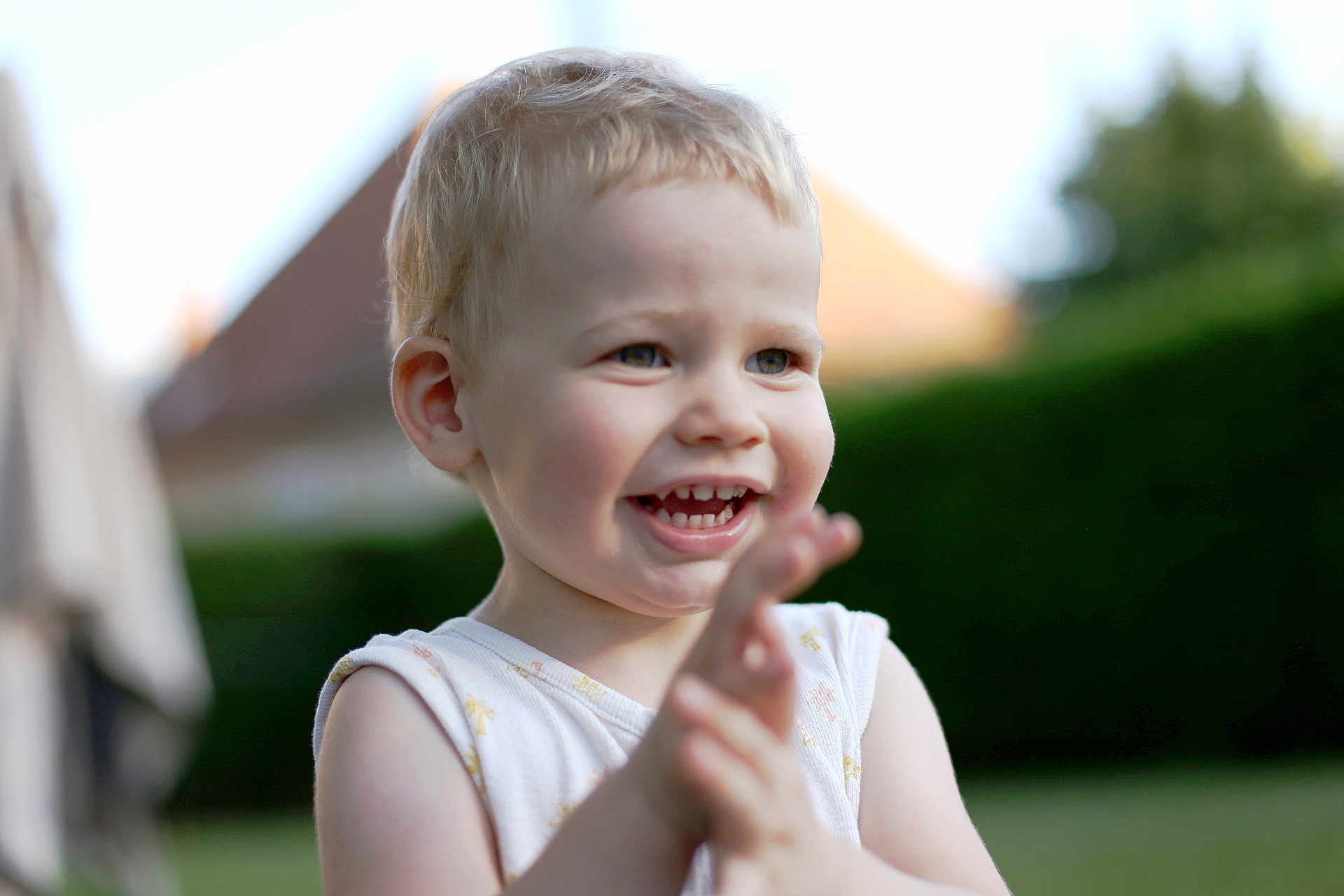 Milo participe au concours pour gagner de l'argent avec cette photo : child, toddler, smiling, clapping, outdoor, daylight, happy, blond_hair, face, person, nature, greenery, shirt, sleeveless, portrait, young_child, expression, cute, playful, skin