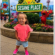 Aubryella joined the competition — help win amazing prizes! child, girl, toddler, smiling, outdoors, theme_park, sesame_place,  amusement_park, sign, elmo, big_bird, abby_cadabby, flowers, garden, playground, rides, pink_shirt, denim_shorts, pink_shoes, portrait