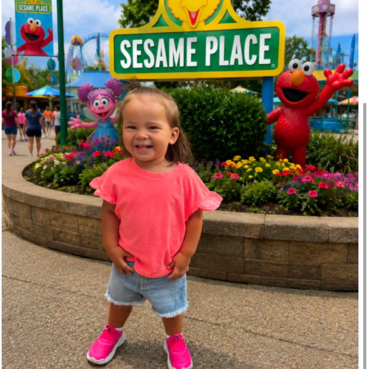 Aubryella joined the competition — help win amazing prizes! child, girl, toddler, smiling, outdoors, theme_park, sesame_place,  amusement_park, sign, elmo, big_bird, abby_cadabby, flowers, garden, playground, rides, pink_shirt, denim_shorts, pink_shoes, portrait