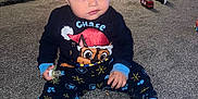 Sami is registered to the contest to win money with this photo: toddler, child, indoor, carpet, pajamas, pacifier, biscuit, toy, cushion, grey_carpet, face, sitting, blue, cute, person, floor, room, clothing, eyes, hair