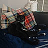 cat, black_cat, indoor, couch, pillow, plaid, blanket, relaxed, pet, animal, feline, domestic, fur, whiskers, collar, resting, cozy, home, curious, seated