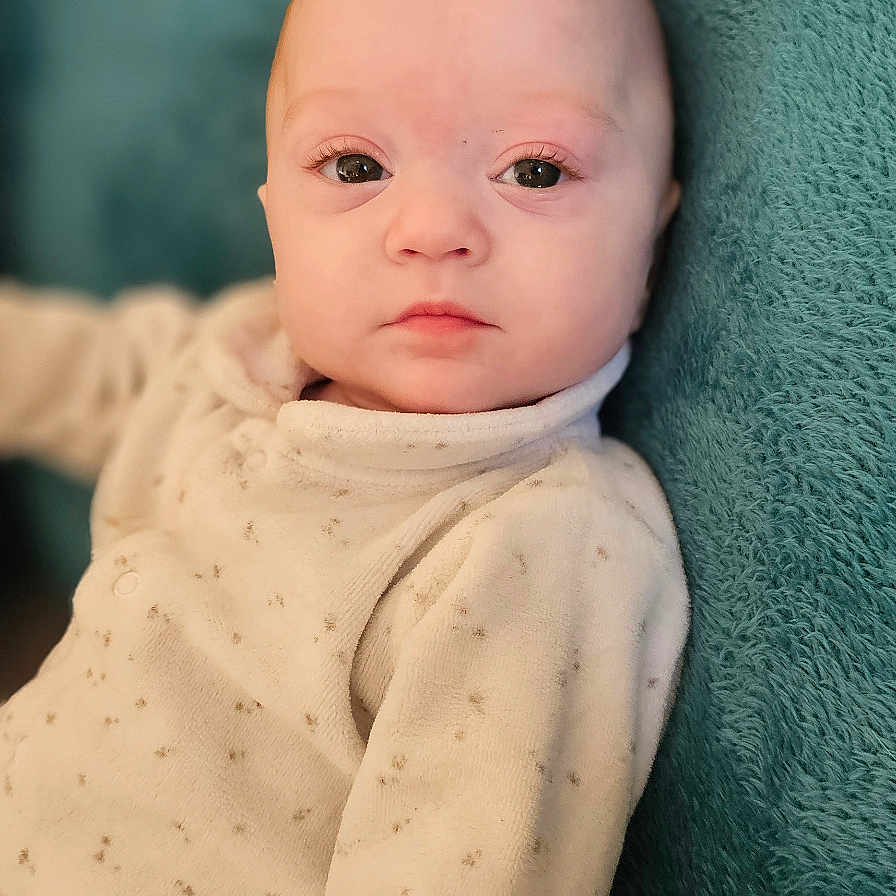 Priya participe au concours pour gagner de l'argent avec cette photo : baby, blanket, child, clothing, cozy, cute, expressionless, eyes, face, head, indoors, infant, pale, person, portrait, sitting, skin, soft, warm, young