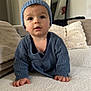 baby, child, crawling, blue_hat, blue_sweater, drool, indoor, cushions, mirror, soft_texture, curious_expression, hands, face, headwear, knitwear, person, portrait, cozy, home, furniture