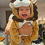 Liam participe au concours pour gagner de l'argent avec cette photo : baby, infant, lion_costume, costume, smiling, happy, person, adult_hands, hood, plush, indoor, living_room, jeans, floor, ceiling_light, open_mouth, bright_eyes, portrait, cute, held