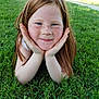 child, freckles, red_hair, grass, outdoor, smile, face, hands, person, nature, park, greenery, casual, daylight, young, happy, portrait, relaxed, summer, skin