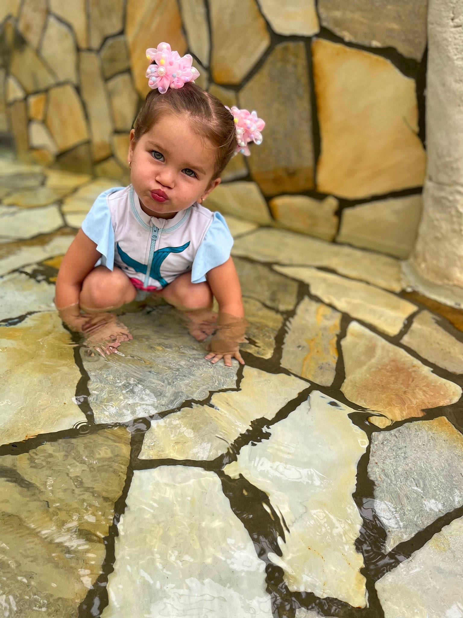 Ariel a rejoint le concours — aidez-le/la à gagner de superbes lots ! baby, baby_toddler_clothing, child, cobblestone, eye, face, fashion_accessory, flagstone, flooring, flower, grass, happy, headband, leisure, person, plant, road_surface, rock, sitting, toddler