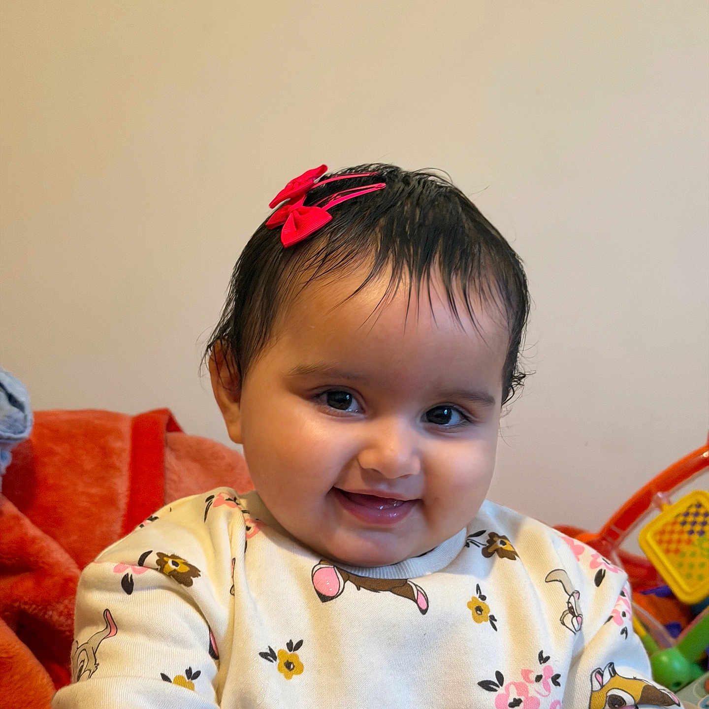 Jind is registered to the contest to win money with this photo: baby, blanket, cartoon_print, child, closeup, clothing, cute, face, happy, indoor, infant, person, playful, portrait, red_bow, smiling, sweater, toy, warm, young_child