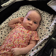 Bianca joined the competition — help win amazing prizes! baby, infant, child, portrait, floral_outfit, dress, bassinet, blanket, bedding, lying_down, indoors, face, eyes, wide_eyed, serious_expression, pacifier, patterned_fabric, close_up, photography, cozy