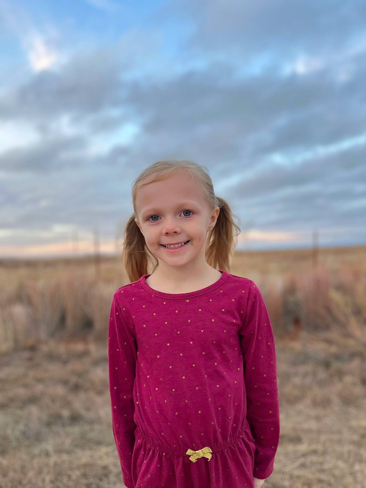 Taytum is registered to the contest to win money with this photo: blond, cloud, electric_blue, face, flash_photography, grass, grassland, hair, happy, joy, landscape, magenta, people_in_nature, person, plant, prairie, shoulder, sky, sleeve, smile