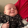 baby, infant, smile, thumbs_up, blanket, onesie, space_pattern, pacifier, hand, person, red_shirt, indoor, sleepy, cute, face, chubby_cheeks, cozy, child, newborn, portrait
