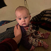 Paisley joined the competition — help win amazing prizes! baby, infant, child, person, bed, hand, pillow, clothing, floral_pattern, purple_shirt, blue_eyes, indoor, blanket, support, cute, sitting, face, skin, expression, home