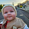 baby, infant, child, face, hat, knit_hat, jacket, beige_jacket, outdoor, street, suburban, smile, closeup, portrait, hand, warm_clothing, evening, soft_light, cute, person