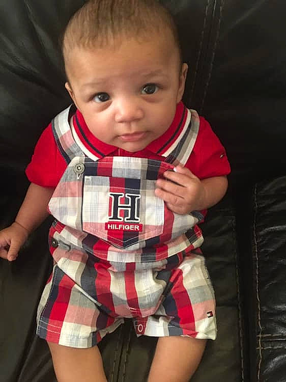 Ezrah is registered to the contest to win money with this photo: arm, baby, baby_products, cheek, child, design, head, pattern, person, plaid, product, sitting, tartan, textile, toddler