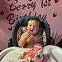 baby, birthday, cake, high_chair, smiling, pink_frosting, messy, celebration, child, first_birthday, face, happy, food, party, decorations, sitting, cute, fun, frosting, strawberry