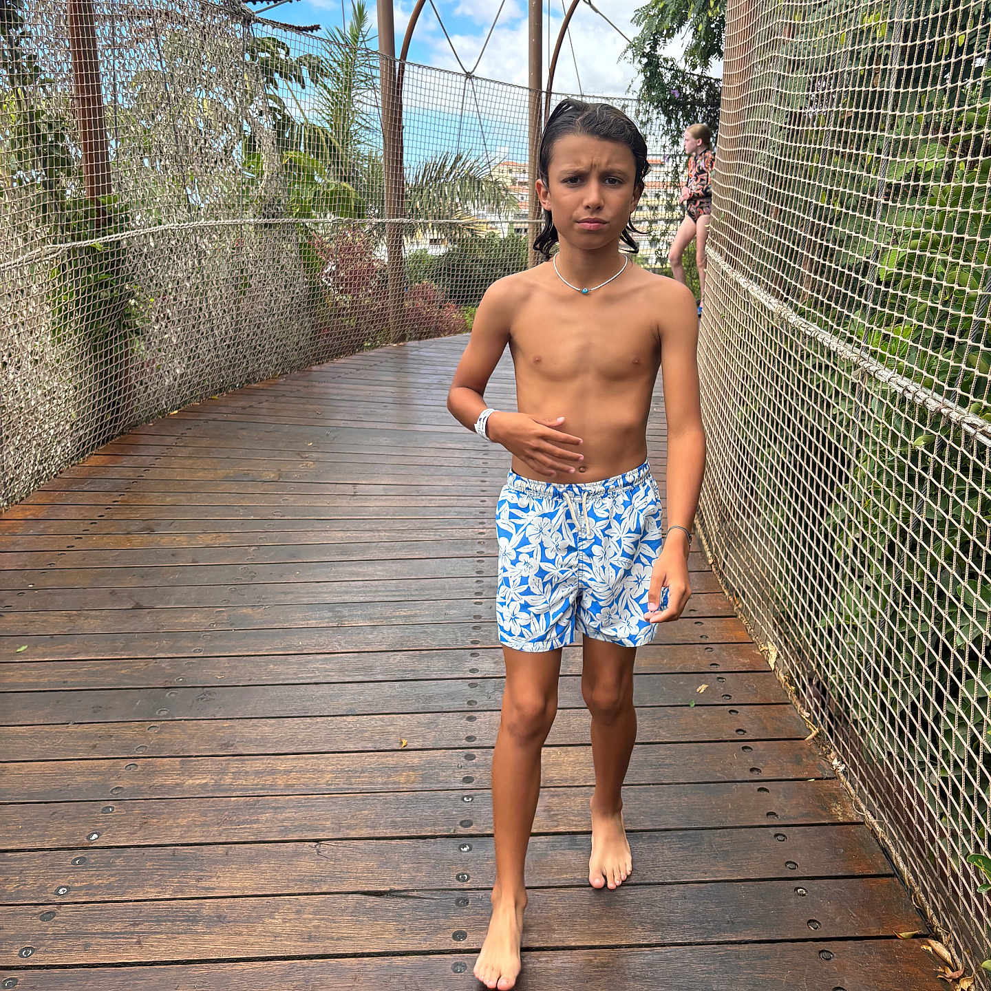 Djulian a rejoint le concours — aidez-le/la à gagner de superbes lots ! background_child, barefoot, boy, bridge, child, confused_expression, fence, necklace, outdoor, patterned_shorts, person, safety_net, sunny_sky, swim_shorts, trees, tropical_plants, vacation, walking, wooden_deck, wristband