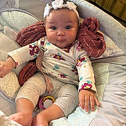 Raelynne is registered to the contest to win money with this photo: baby, infant, headband, flower, padded_seat, blanket, cushion, clothing, long_sleeve, leggings, indoor, face, child, cute, expression, hand, foot, comfort, soft, seated