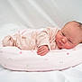 Emie-Grace is registered to the contest to win money with this photo: newborn, baby, infant, pink_onesie, cushion, floral_pattern, soft, sleeping, lying_down, white_background, cute, child, portrait, indoors, cozy, small_hand, head, peaceful, skin, baby_bed