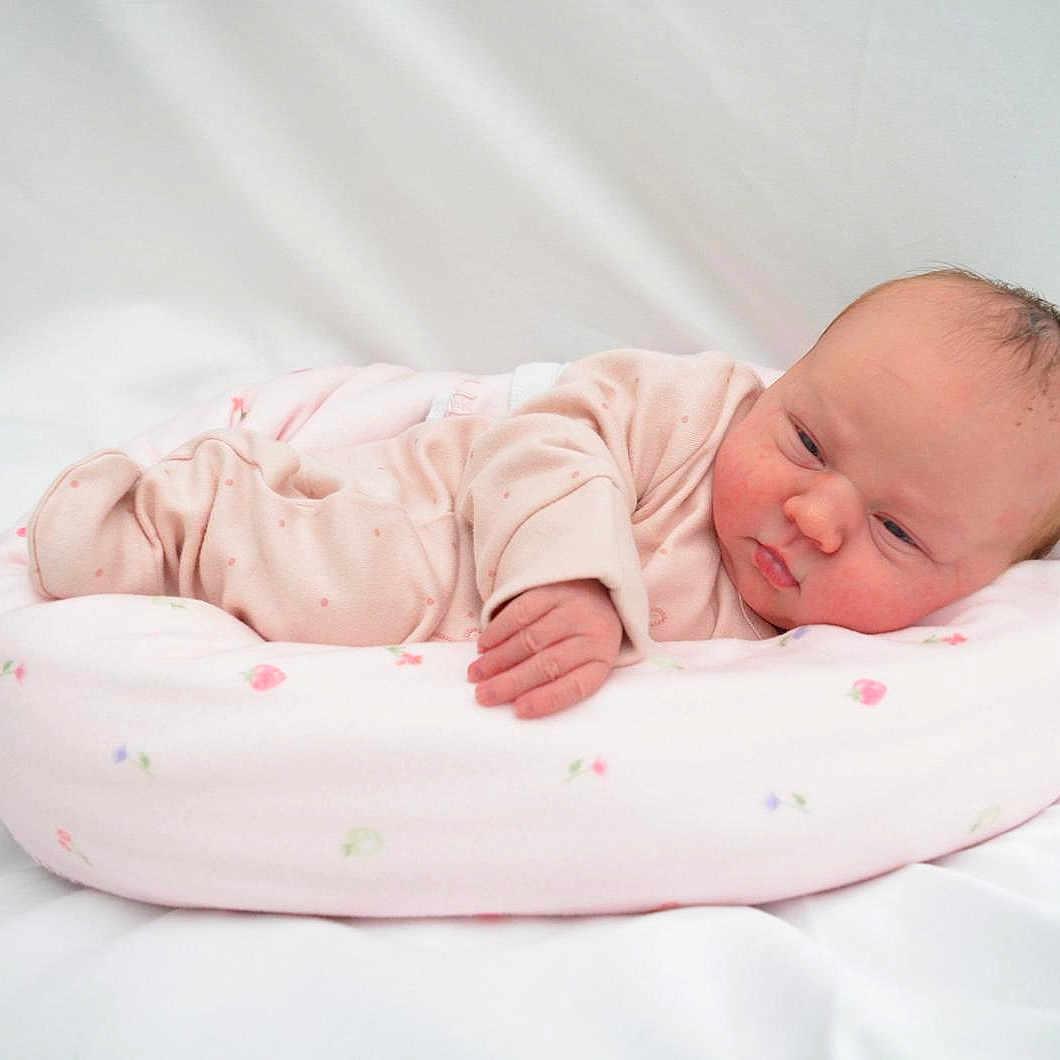 Emie-Grace is registered to the contest to win money with this photo: baby, baby_bed, child, cozy, cushion, cute, floral_pattern, head, indoors, infant, lying_down, newborn, peaceful, pink_onesie, portrait, skin, sleeping, small_hand, soft, white_background