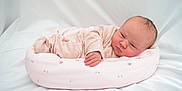 Emie-Grace is registered to the contest to win money with this photo: newborn, baby, infant, pink_onesie, cushion, floral_pattern, soft, sleeping, lying_down, white_background, cute, child, portrait, indoors, cozy, small_hand, head, peaceful, skin, baby_bed