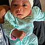 baby, infant, child, onesie, headwrap, bow, patterned_clothing, mint_green, pink, hand, face, eyes, carpet, person, holding, cute, newborn, indoor, portrait, cozy