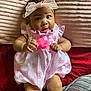 baby, child, infant, dress, headband, bow, pink, heart_pattern, blanket, lying_down, cute, chubby_cheeks, indoors, soft_texture, fabric, person, skin, legs, hands, curious
