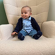 Raphaël participe au concours pour gagner de l'argent avec cette photo : baby, child, armchair, blue_shirt, cardigan, jeans, socks, tongue_out, playful, indoor, cozy, furniture, smiling, cute, seated, person, young, happy, casual_clothing, home