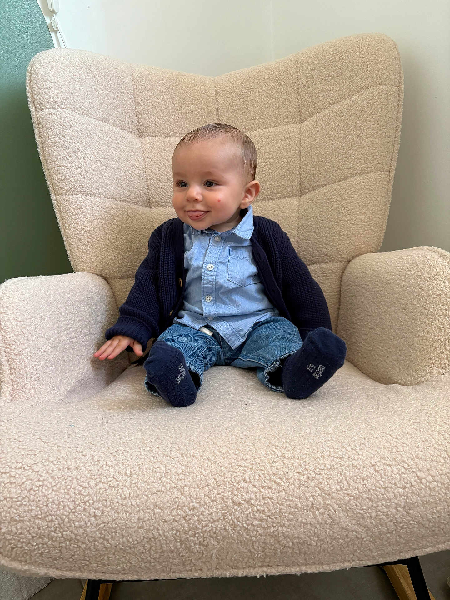 Raphaël participe au concours pour gagner de l'argent avec cette photo : baby, child, armchair, blue_shirt, cardigan, jeans, socks, tongue_out, playful, indoor, cozy, furniture, smiling, cute, seated, person, young, happy, casual_clothing, home